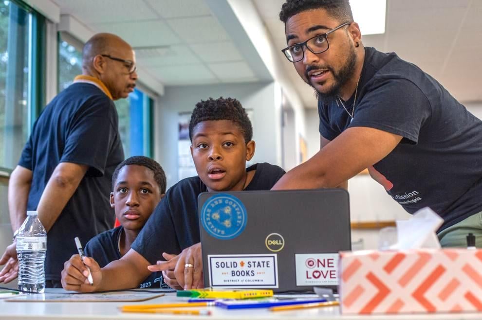 Daniel Fairley works with young students in a school classroom