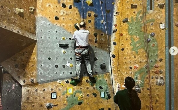 A person climbing an indoor rock wall with belay