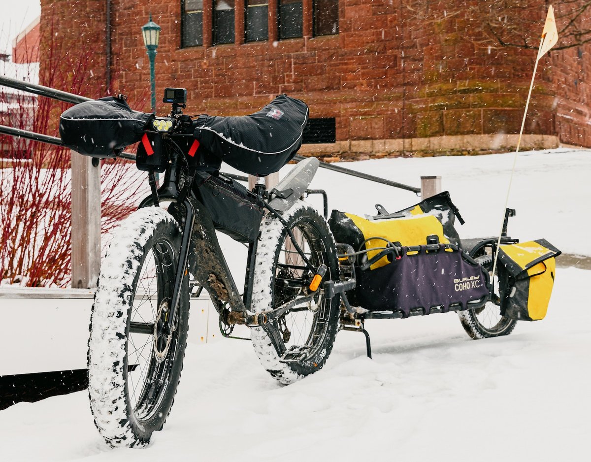 A bike on campus in the snow with a trailer attached